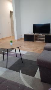 a living room with a table and a flat screen tv at Apartman Sanja Ledine in Ledine