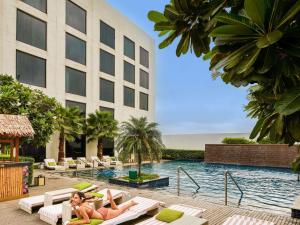 two women laying on lounge chairs in a pool at a hotel at Pullman New Delhi Aerocity in New Delhi