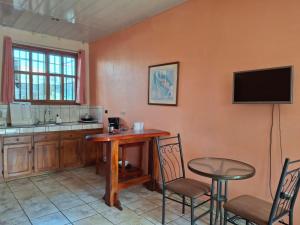 a kitchen with a table and a tv on the wall at Quepos Studio Apartments in Quepos