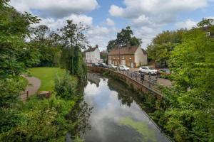a river in a town with cars parked next to it at Charming Wootton in Hail Weston