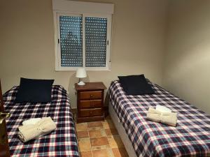 two beds sitting in a room with a window at La casa del rio cauche in Almogía +11 photos