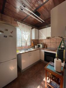 a kitchen with white appliances and a wooden ceiling at La casa del rio cauche in Almogía