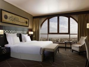 a bedroom with a large bed and a large window at Zamzam Pullman Madina in Medina