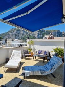 a patio with blue umbrellas and chairs on a roof at Romy Blu in Capri