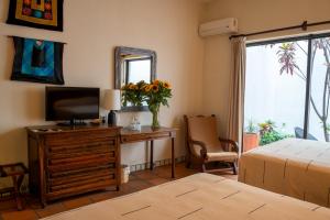 a bedroom with a television and a dresser with a mirror at Parador del Dominico in Oaxaca City