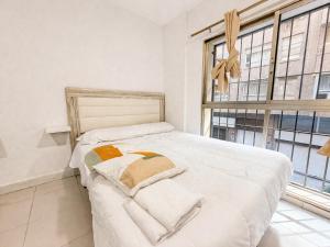 a white bed in a room with windows at Alicante Beach Hostel in Alicante