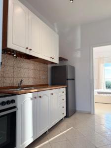 a kitchen with white cabinets and a refrigerator at Casa Boha Garden in Dhërmi