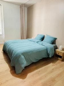 a bedroom with a bed with a blue blanket at Copacabane in Gujan-Mestras