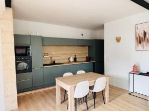 a kitchen with a wooden table and white chairs at Copacabane in Gujan-Mestras