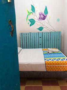 a bed with a blue headboard with a flower on the wall at The Best Adventure Hostel in San Gil +61 photos