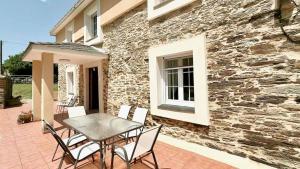 a table and chairs on a patio in front of a building at The Cliffs - Casa Cadaval in Santa Marta de Ortigueira