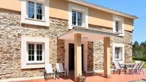 a house with chairs and a table in front of it at The Cliffs - Casa Cadaval in Santa Marta de Ortigueira