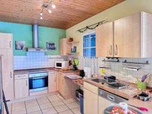 a large kitchen with wooden cabinets and a sink at La Pierre Lotie in Saint-Denis-dʼOléron