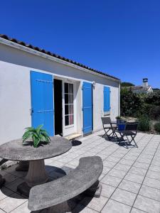 a patio with a table and chairs and blue doors at La Pierre Lotie in Saint-Denis-dʼOléron