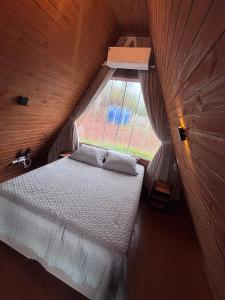 a bedroom with a bed in a wooden room with a window at Amorência Chalé Luz da lua in Campo Largo