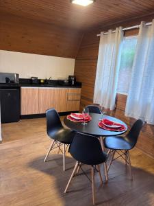 a dining room with a table and chairs and a kitchen at Amorência Chalé Luz da lua in Campo Largo