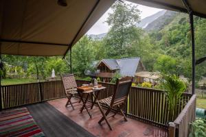 a patio with a table and chairs on a deck at Aloha Riverside in Kasol
