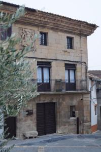 Edificio de piedra antiguo con ventanas y balcón en Casa El Carolino, en Larraga
