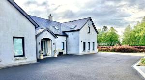 a white house with a driveway in front of it at Ardbrin Lodge Guest Accommodation in Dunadry