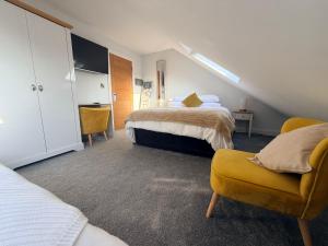a bedroom with two beds and a yellow chair at Ardbrin Lodge Guest Accommodation in Dunadry