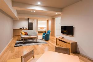 a living room with a couch and a tv at HAKODATE Uminokaze in Hakodate