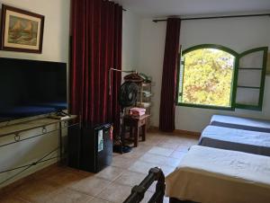 a bedroom with two beds and a tv and a window at Pousada rotas e ritmos in São Paulo