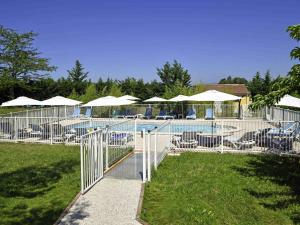 a pool with tables and chairs and umbrellas at Ibis Budget Sisteron in Sisteron