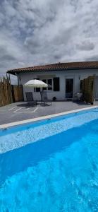 a blue swimming pool with an umbrella and a house at Studio Coeur Basque in Iholdy
