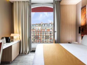 a hotel room with a bed and a large window at Mercure Paris Alesia in Paris +95 photos