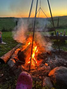 a campfire with a person sitting next to it at Leśny Zakątek - Mazury - Warmia - jezioro Dadaj in Ramsowo