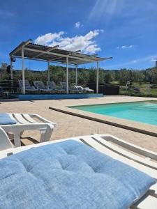 a pool with chairs and a pavilion next to a swimming pool at Tenuta Don Ballore Country Resort in Galtellì