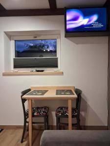 a table and two chairs in a room with a television at Noclegi Radoch Mazury in Ruciane-Nida +3 photos