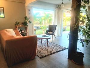 a living room with a couch and a table at Maison créole chaleureuse - Centre Sud Martinique in Ducos +4 photos