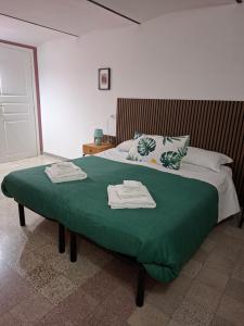 a bedroom with a green bed with two towels on it at Dimora Tre Marie in LʼAquila