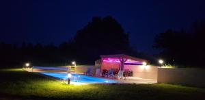 a swimming pool at night with a building with purple lights at La truffière in Belvès