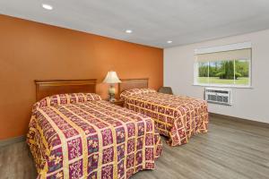 two beds in a hotel room with orange walls at Village Lodge in Bristol