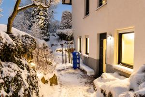 a snow covered sidewalk next to a building with a blue fire hydrant at Ferienwohnung Zum Sperberring - Parkplatz - Wallbox - WLAN - Netflix&Disney - sehr ruhig - perfekt zum entspannen & erholen in Ilmenau