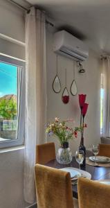 a dining room with a table with flowers and a window at Apartman Mara in Risan