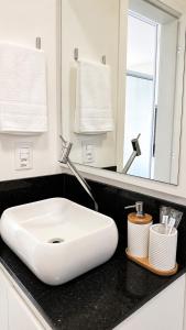 a bathroom with a white sink and a mirror at MaxLoft - Studio Moderno in Joinville