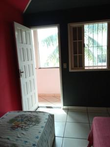 an open door to a room with a bed and a window at Refúgio à beira mar in Serra