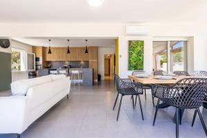 a living room with a white couch and a table and chairs at Ensemble Villa et Studio Piscine Proche Plage in Valras-Plage