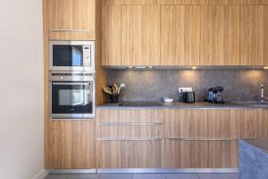 a kitchen with wooden cabinets and stainless steel appliances at Ensemble Villa et Studio Piscine Proche Plage in Valras-Plage