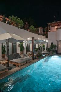 een zwembad met ligstoelen en parasols 's nachts bij Casa Beu Hotel Boutique in Puerto Escondido