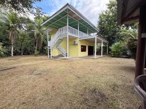 a yellow house with a staircase in a yard at Casa Melda Walk to the Beach & Gandoca-ManzanillO in Manzanillo
