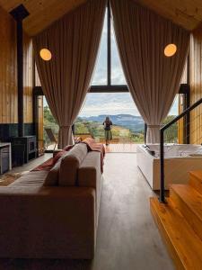 a room with a bed and a large window at Villa Alpina - Cabanas Conceito - Vale dos Vinhedos in Bento Gonçalves