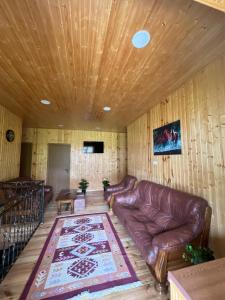 a living room with a leather couch and a rug at Kazbegi Vibe in Kazbegi