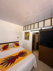 a bedroom with a bed and a flat screen tv at Aremiti - Fare Orotia in Taputapuapea