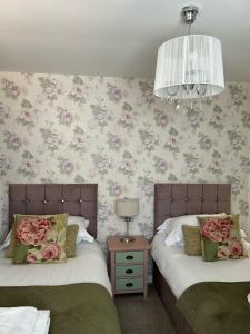 two beds in a bedroom with flowers on the wall at The Royal George Cottingham in Cottingham