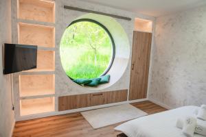 ein Schlafzimmer mit rundem Fenster und Fernseher in der Unterkunft Infinity View Chalet in Valea Doftanei