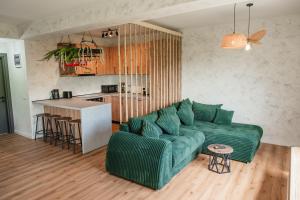 ein Wohnzimmer mit einer grünen Couch und einer Küche in der Unterkunft Infinity View Chalet in Valea Doftanei